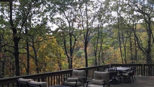 Eine Holzterrasse mit Gartenmöbeln, umgeben von Bäumen.