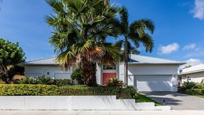 Ein modernes, zweistöckiges Haus mit weißer Fassade, einer roten Tür und einer Garage.