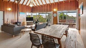 Un vaste espace de vie doté d’un plafond en bois, d’une grande table à manger et de sièges confortables.