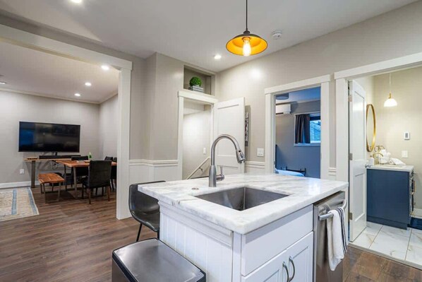 A modern kitchen with a marble countertop, a built-in sink, and a pendant light. - Fremont Haven: Bright, Comfortable & Central (Seattle)