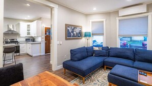 Una cocina moderna con armarios blancos, un comedor con mesa de madera y un juego de sofá azul.