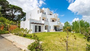 Een modern huis met twee verdiepingen, een witte gevel, een stenen muur en een verharde oprit.