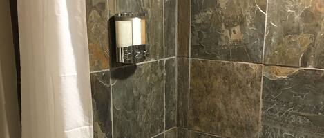 A bathroom with a bathtub, a showerhead, and a towel rack.