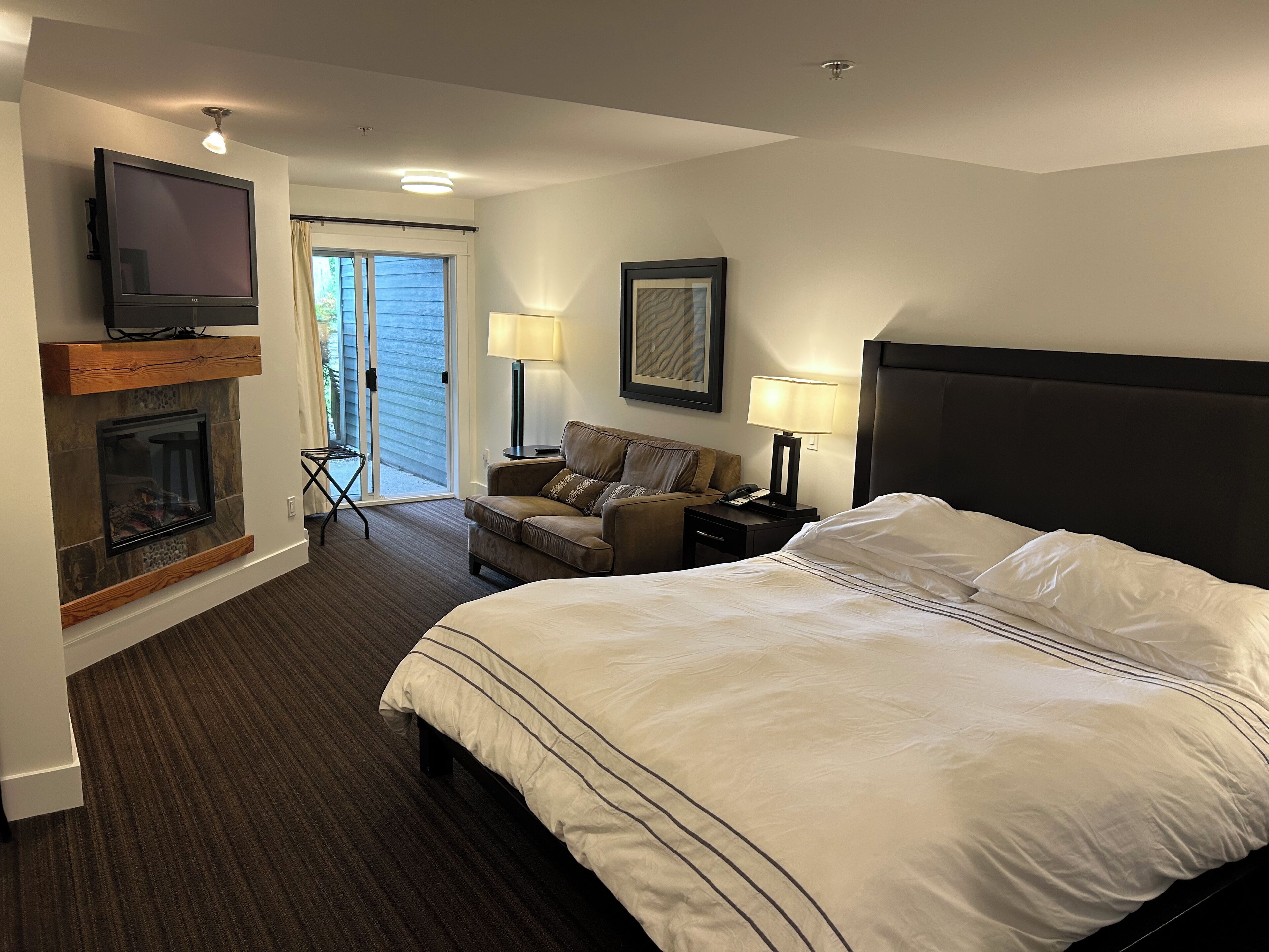 Une chambre d’hôtel équipée d’un lit, d’une télévision, d’une cheminée, d’un canapé, d’une table de chevet et d’une lampe.