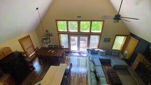 A spacious living area with a dining table, a sofa, and a ceiling fan.