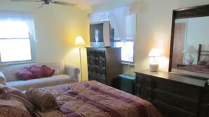 Un dormitorio con cama, cómoda y televisor sobre un mueble.