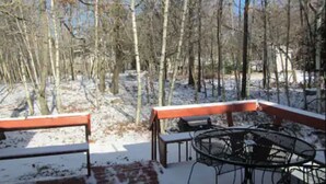 Un espacio al aire libre cubierto de nieve, con una mesa metálica y bancos.
