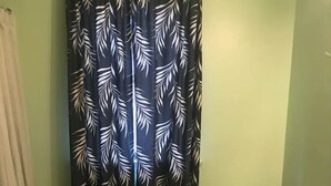 Un baño con inodoro, lavabo y cortina de ducha con estampado de hojas.