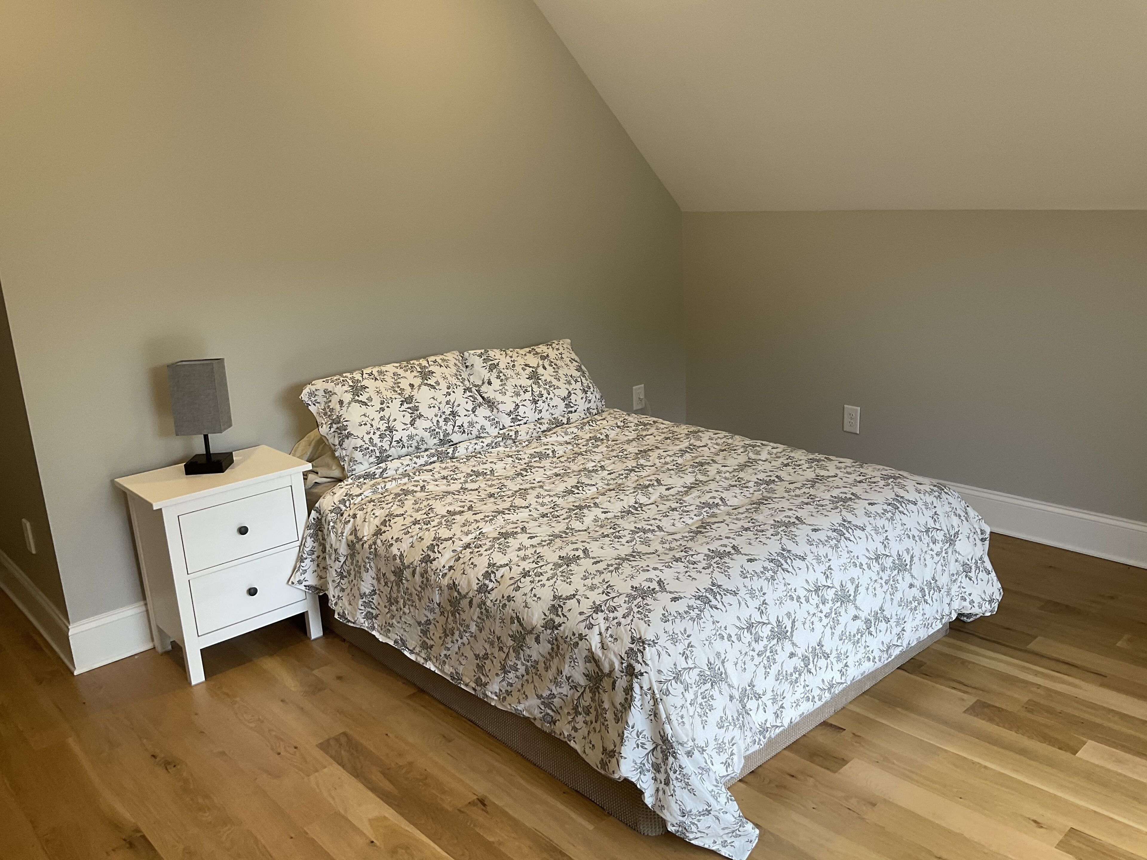 A bedroom with a bed, a nightstand, and a lamp.