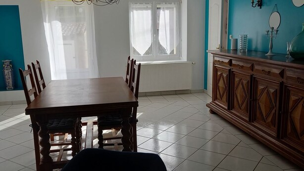 Ein Essbereich mit einem Holztisch, Stühlen, einer blauen Wand und einer Vitrine mit Dekoration.