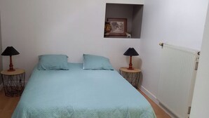 Ein Schlafzimmer mit einem Bett, zwei Nachttischen mit Lampen, einer kleinen Ablage mit einem Bild und einer Heizung.