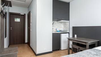 Une chambre d’hôtel compacte comprenant un coin cuisine, un lit et une petite table.