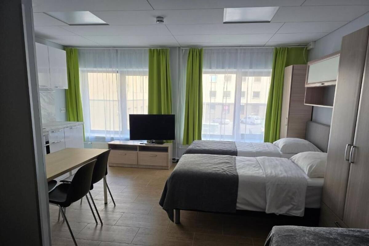 A hotel room with a bed, a desk, a chair, a television, and a wardrobe.