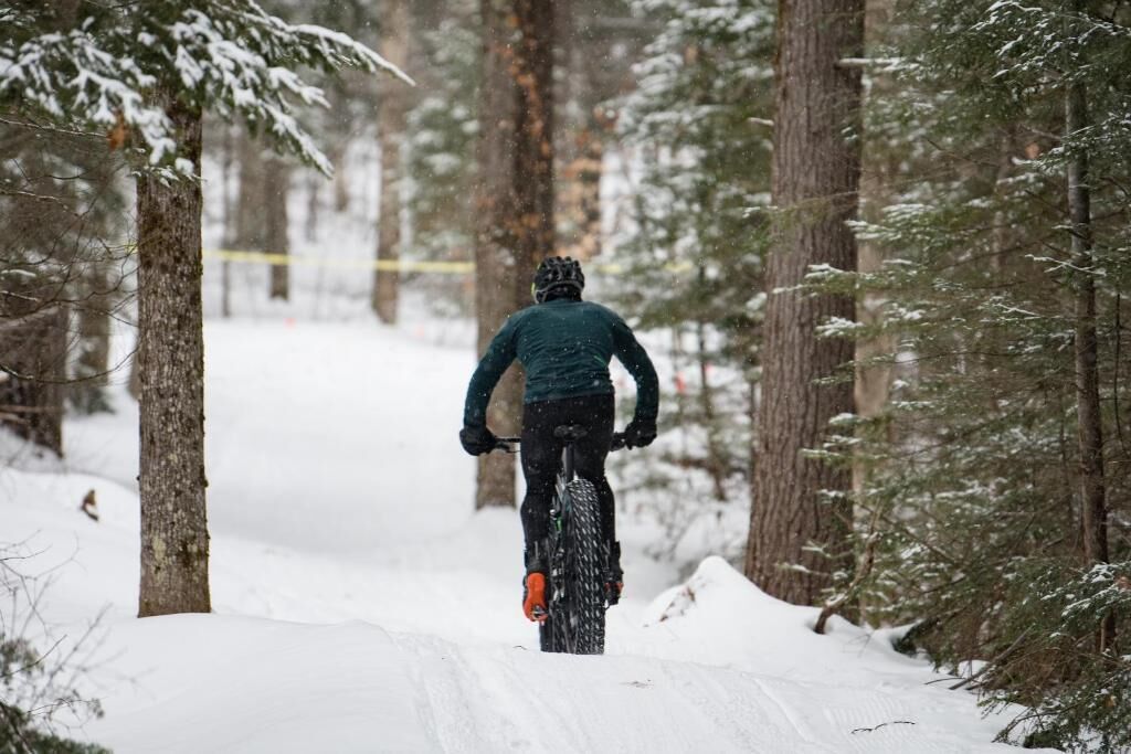 A person riding a mountain bike through a snowy forest trail.