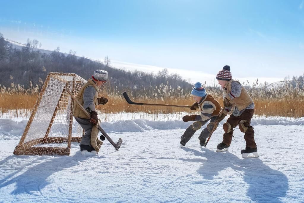 A group of people playing hockey on a snowy field with a goal net.