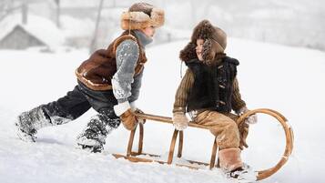 Two children sledding in a snowy outdoor setting.