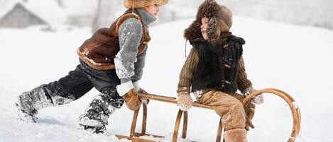 Two children sledding in a snowy outdoor setting.