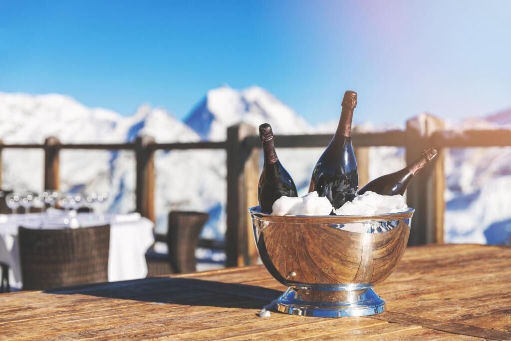 A wooden table with a metal bowl containing two bottles and a spoonful of ice cream.
