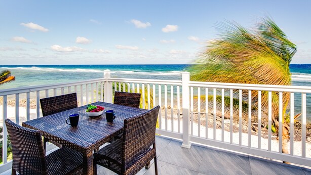Um terraço com mesa e cadeiras com vista para o oceano.