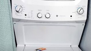 Vue de face d’un lave-linge blanc, avec ses boutons de commande et son compartiment à lessive.