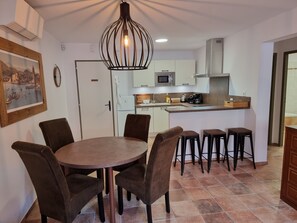 A modern kitchen with white cabinets, a microwave, and a coffee maker. There is a dining area with a round table and six chairs.