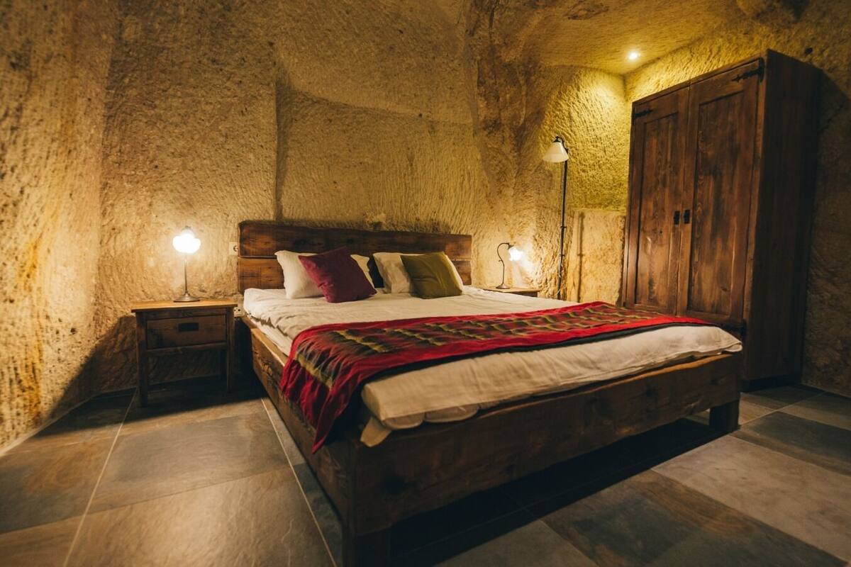 A bedroom with a wooden bed, two bedside lamps, a nightstand, and a wardrobe.