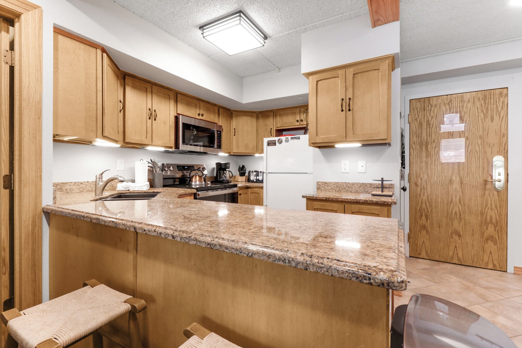 A kitchen with wooden cabinets, granite countertops, stainless steel appliances, and a built-in oven.