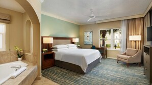 A hotel room with a large bed, a separate bathroom with a bathtub, a desk with a chair, a TV, and a window with curtains. - Sheraton Vistana Resort in Orlando, Florida (includes Christmas weekend) (Orlando)