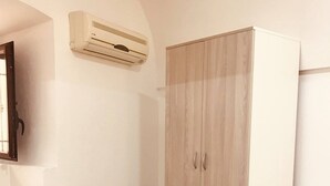 A room with a wardrobe, a chair, and an air conditioning unit. - Vacation Home PETRA (Modica)