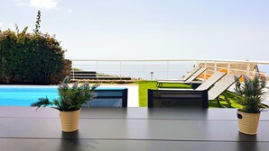 Et poolområde med liggestole, en pool og plantekasser.