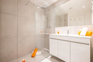 Une salle de bain moderne avec une douche, un lavabo et un miroir.