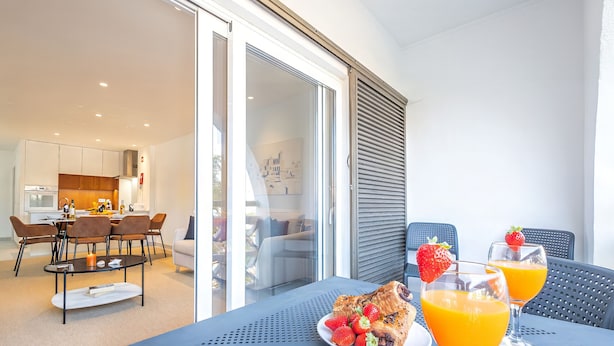A modern dining area with a table set for two, featuring a croissant, strawberries, and orange juice. - Comfortable apartment with pool in Albufeira (Albufeira)