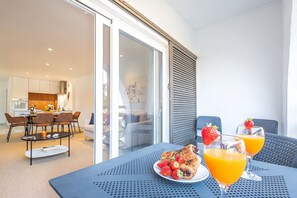 Un comedor moderno con una mesa dispuesta para dos, con un croissant, fresas y jugo de naranja.