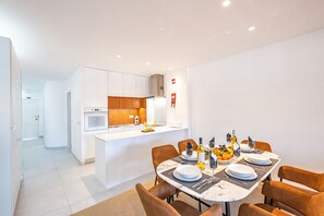 A modern kitchen with white cabinets, a central island, and a dining area with a table set for four.