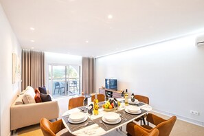 Una sala de estar moderna con comedor, sofá, televisor y balcón.