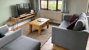 Una sala de estar con televisión, sofá y mesa de centro.