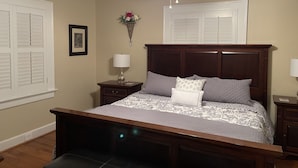 Une chambre à coucher comprenant un lit, des tables de chevet, un ventilateur de plafond et un luminaire fixé au mur.