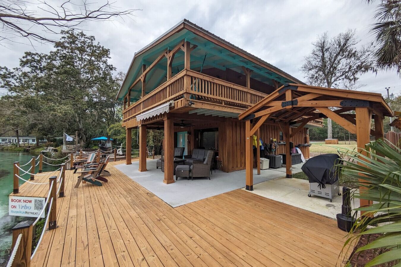 A wooden deck with lounge chairs, a covered seating area, and a grill.