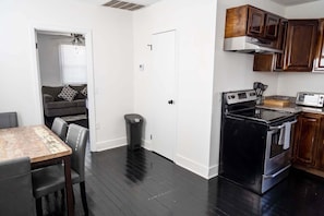 Une cuisine compacte avec un poêle noir, des armoires en bois et un coin repas comprenant une table et des chaises.