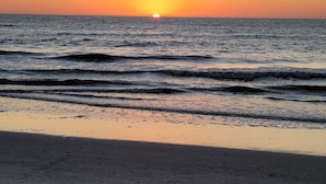 Una playa al atardecer con olas acercándose a la orilla.
