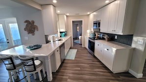 Una cocina moderna con armarios blancos, una isla central y un comedor con dos sillas.