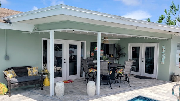 Un patio techado con piscina, mobiliario exterior y una mesa de comedor.