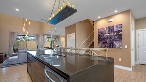 A modern kitchen with a central island, stainless steel appliances, and a large window with curtains.