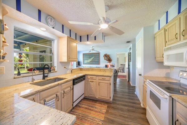 A kitchen with wooden cabinets, a built-in dishwasher, a stove, and a ceiling fan.
