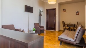 Una sala de estar moderna con un sofá, una mesa de comedor y un televisor de pantalla plana montado en la pared.