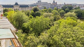 Un paisaje urbano que combina edificios históricos y modernos, abundante vegetación y un cielo despejado.