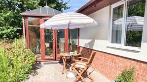 Eine Terrasse mit Tisch und Stühlen, einer Glastür und einer Ziegelwand.