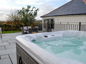A hot tub with a control panel, a patio area with outdoor furniture, and a view of a house with a garage in the background. - 3 bedroom accommodation in Amisfield (Amisfield)