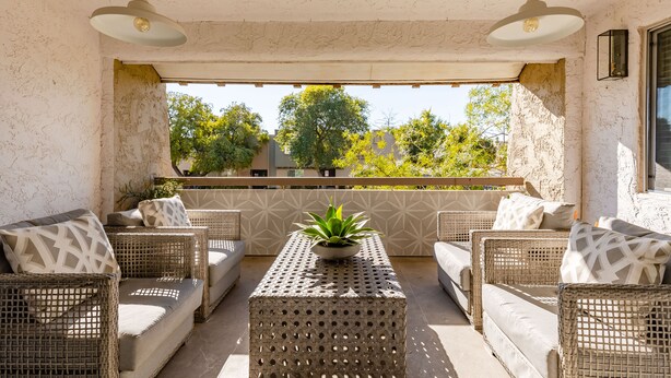 A sunlit outdoor seating area with wicker furniture and a central table, featuring a potted plant. - Ultra-Clean, Designer Condo in Downtown Scottsdale (Scottsdale)