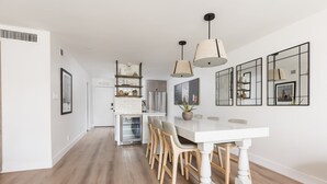 A modern kitchen with a central island, wooden chairs, pendant lights, and a white dining table. - Ultra-Clean, Designer Condo in Downtown Scottsdale (Scottsdale)